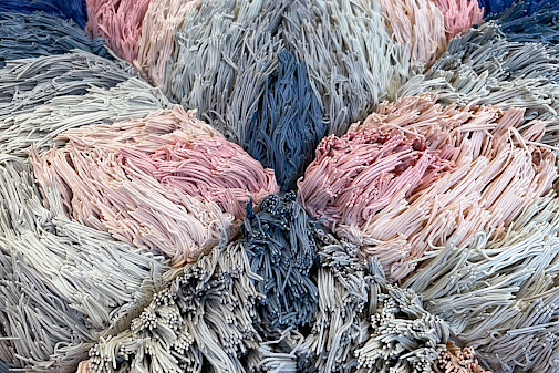 Detail photo of a pink and blue ceramic sculpture of a geometric patterned shag rug by Risa Hricovsky.