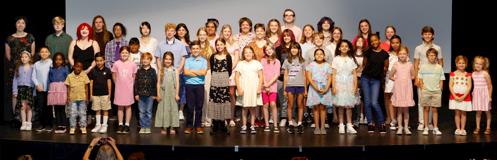 Photo of a group of children smiling on a stage.