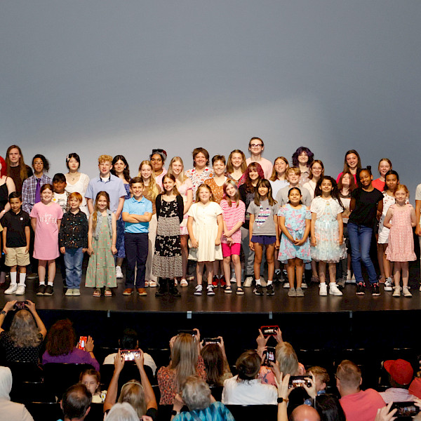 Photo of a group of children smiling on a stage.