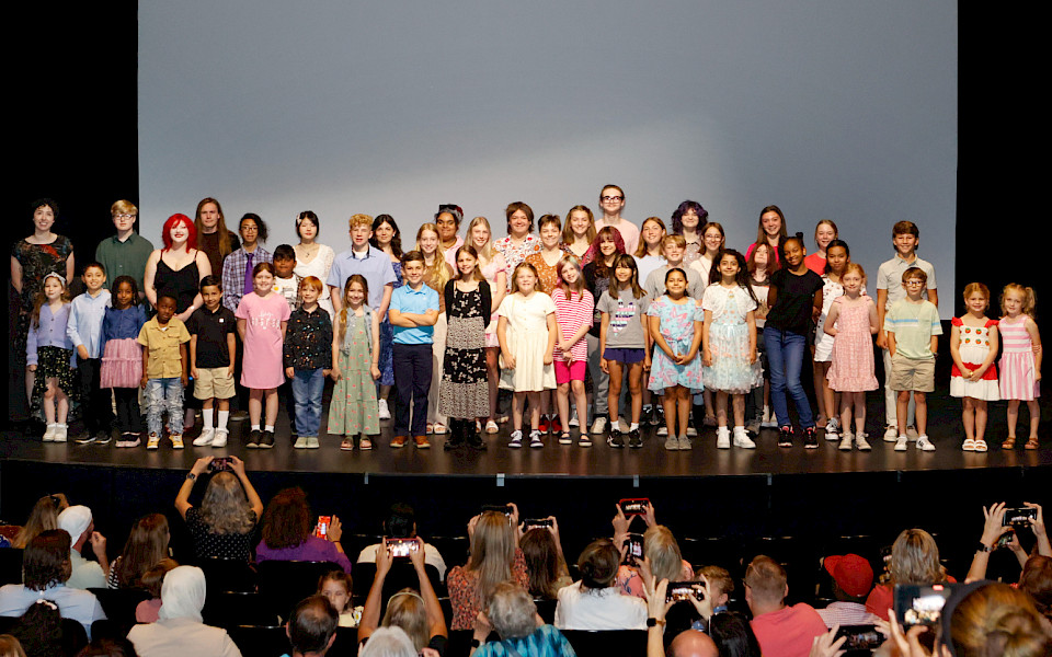 Photo of a group of children smiling on a stage.