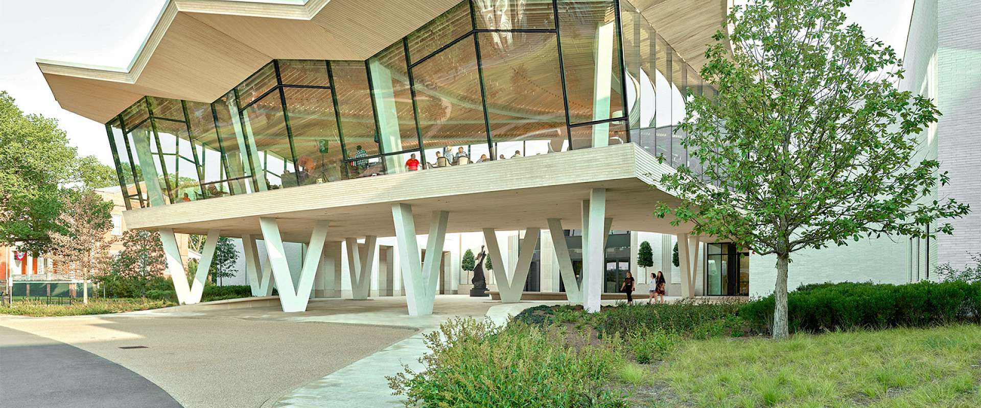 Photo of the Courtyard Entrance to the Arkansas Museum of Fine Arts. People are visible in the Cultural Living Room on the second floor.