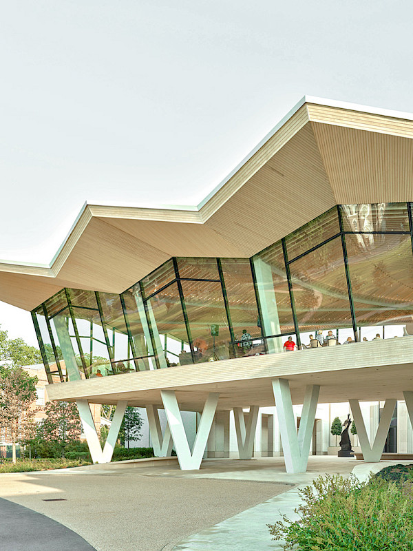 Photo of the Courtyard Entrance to the Arkansas Museum of Fine Arts. People are visible in the Cultural Living Room on the second floor.