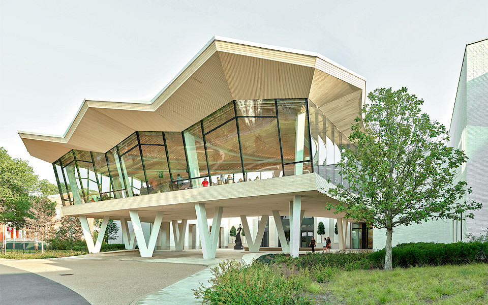Photo of the Courtyard Entrance to the Arkansas Museum of Fine Arts. People are visible in the Cultural Living Room on the second floor.