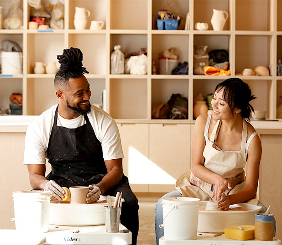 Photo of two people wearing goggles and hammering metal in an art studio.